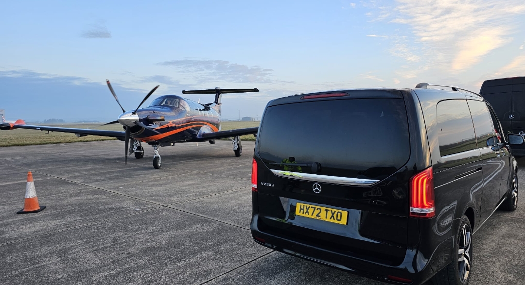 Black Mercedes-Benz V-Class on the apron beside a charter turboprop — Primex Chauffeurs